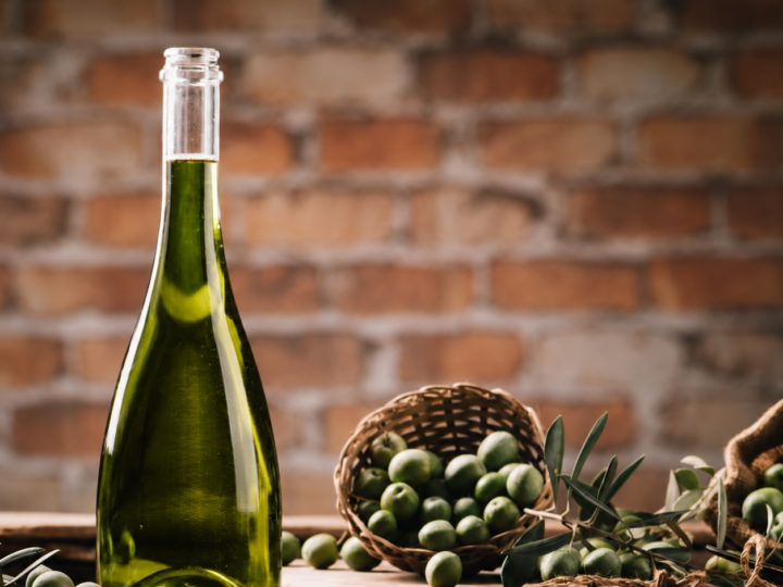 Botella de aceite de oliva junto a una cesta de aceitunas