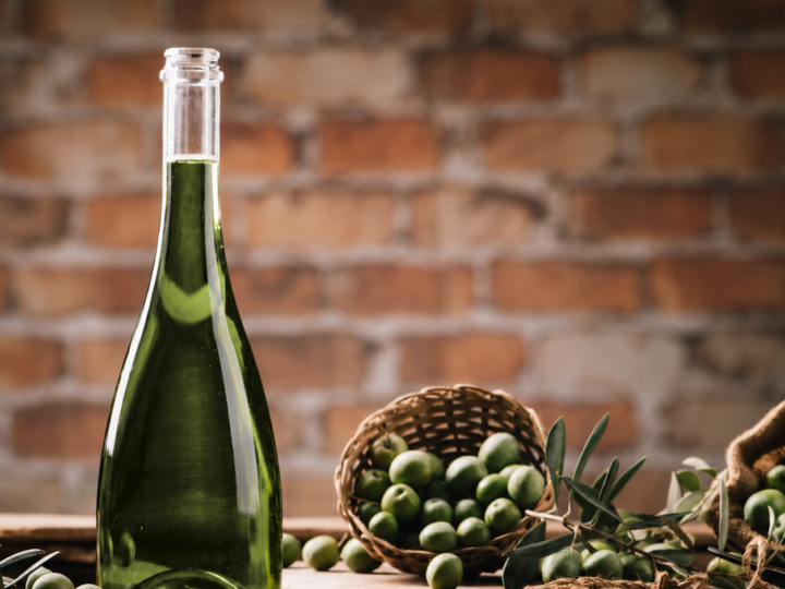 Bottle of extra virgin olive oil beside a basket of olives